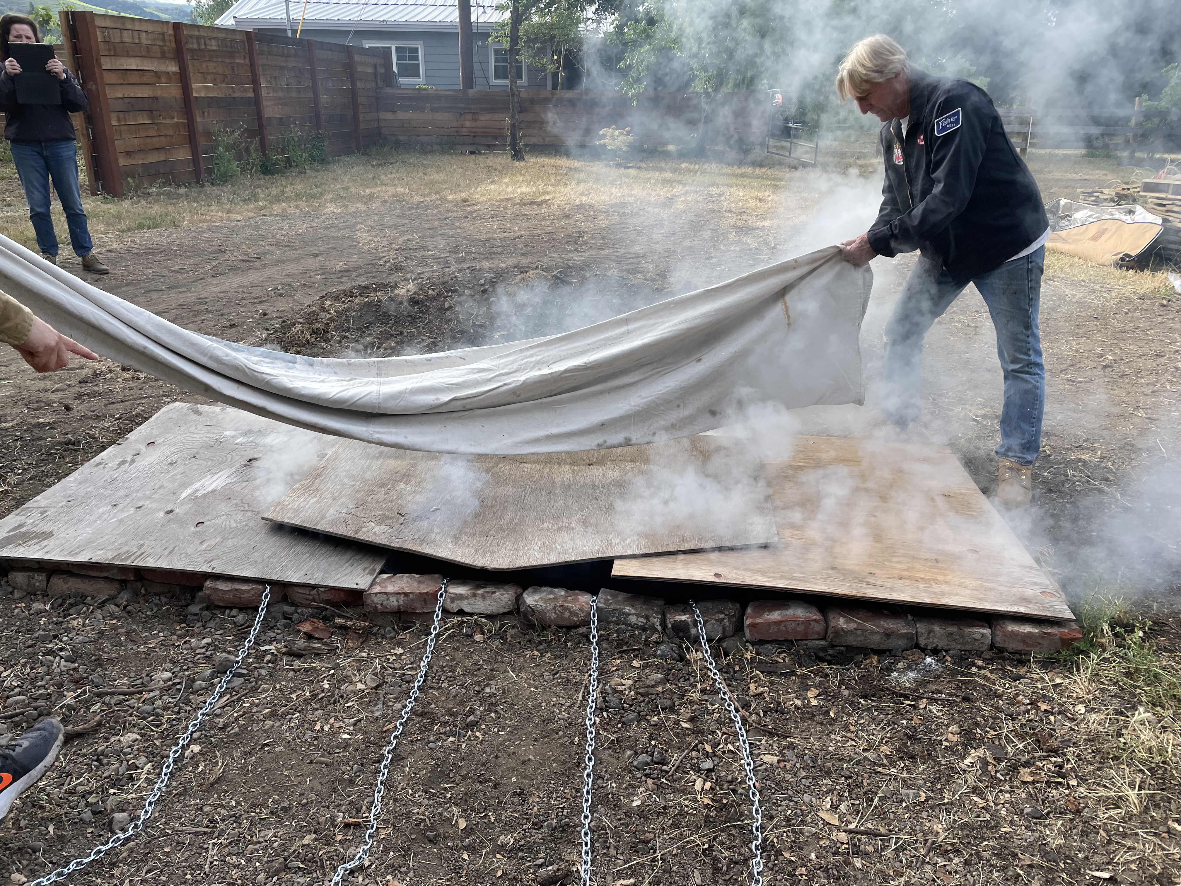 Laying canvas over the plywood lid. It&rsquo;s good to use a single piece of canvas or tarp big enough to cover the whole pit, as you can then easily fold it back and move all the soil off in a single action afterwards.